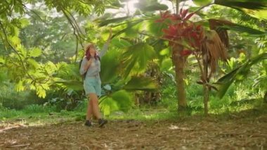 Woman contemplating tropical rainforest, sun light shining through with flare 4K