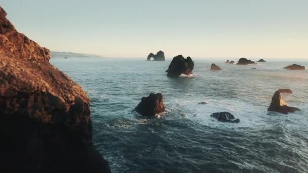 Drone volant rapidement entre les rochers scéniques de haute mer sombre, Vue aérienne coucher de soleil — Video