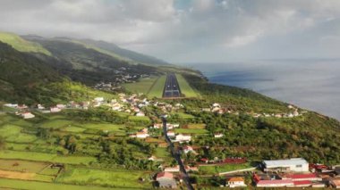 Sao Jorge Adası, Azores 'teki yeşil manzaralı köy evlerinin üzerinden uçan uçak.
