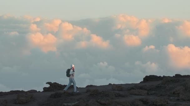 Colpo epico mozzafiato di donna trekking montagna sopra le nuvole rosa tramonto dorato — Video Stock