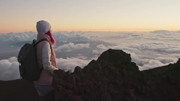 Paisaje nuboso cinematográfico al atardecer, mujer con mochila senderismo montaña volcánica 4K — Vídeos de Stock