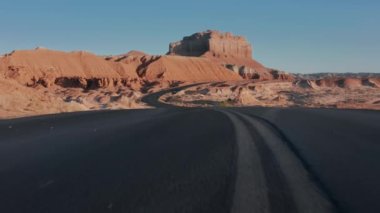 Sinema kırmızı çölünde asfalt yolda alçaktan uçan bir dron.