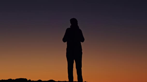 Menschliche Silhouette auf Himmelshintergrund. Reisende genießen filmischen Sonnenuntergang 4K — Stockvideo