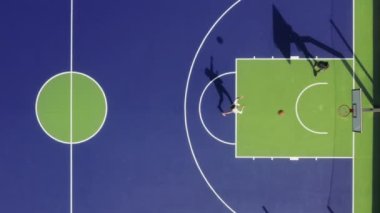 İki adam renkli bir kortta oynuyor, tepeden görüldüğü gibi.