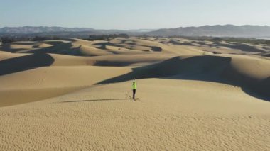 Kadın, VR 'da gün doğumunda kum tepesinde ruhani yoga pozu veriyor.
