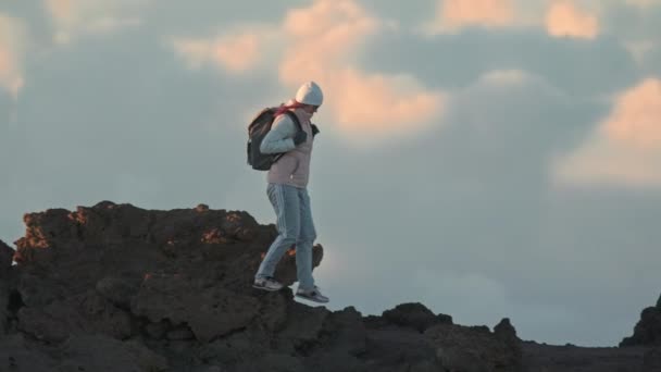Mujer activa caminando en el borde de la montaña del volcán en un fondo nuboso soleado — Vídeos de Stock