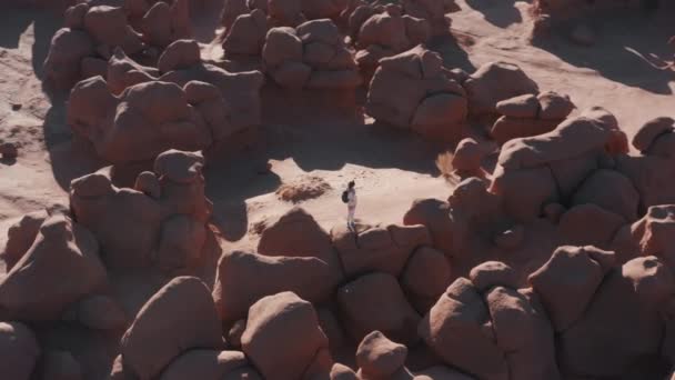 Drone flying around traveler on top pink sandstone hoodoo formation at sunrise — Stock Video