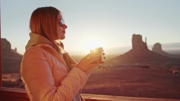 Frau trinkt Tee in Tasse, entspannt sich auf der Terrasse, sonniger Morgen im Monument Valley — Stockvideo