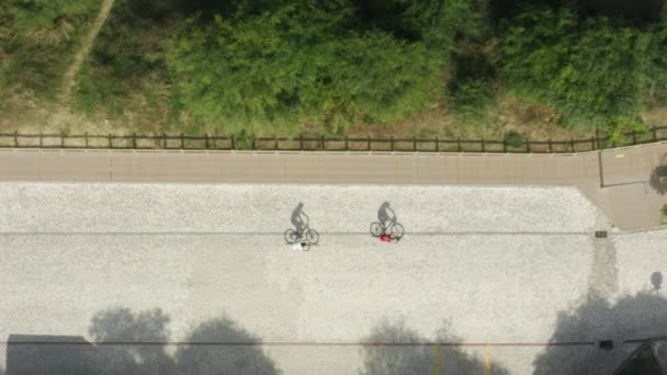 Ciclistas viajan dentro de una playa cerca de vehículos estacionados — Vídeo de stock