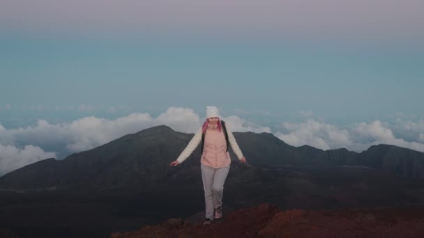 Feliz mujer sonriente de los años 30 subiendo la montaña del volcán Haleakala al atardecer rosa 4K — Vídeo de stock