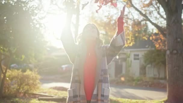 Femme heureuse souriante jetant des feuilles d'érable rouge sèches dans les airs, Feuillage d'automne — Video