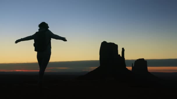Ευτυχισμένος ταξιδιώτης γυναίκα αυξάνεται τα χέρια κατά την ανατολή ή το ηλιοβασίλεμα στην έρημο Monument Valley — Αρχείο Βίντεο