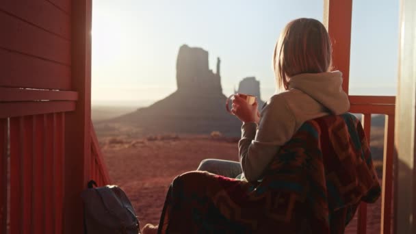 Ung kvinna på stuga terrass med utsikt över filmisk natur landskap i soluppgången 4K — Stockvideo