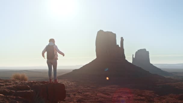 Kvinna resenär med armar upp på toppen av berget tittar på Monument Valley — Stockvideo