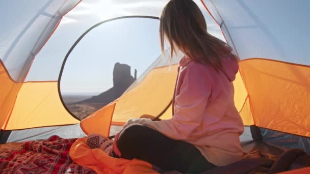Jonge vrouw opent oranje campingtent bij prachtig Monument Valley landschap 4K — Stockvideo