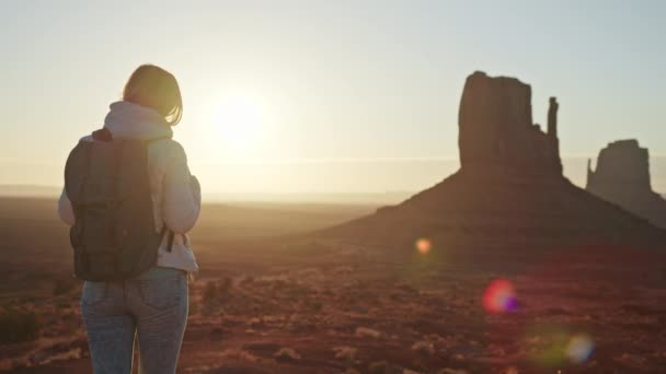 Turista mujer en el paisaje del desierto al amanecer, rayos de sol dorados destellos acantilados rojos — Vídeo de stock