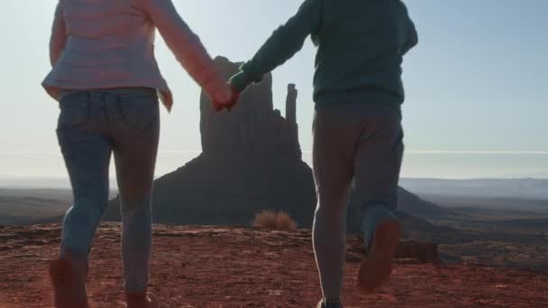 一对快乐的夫妇在纪念碑谷地旅行，跳跃，举起双臂 — 图库视频影像