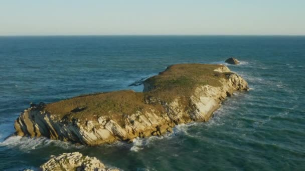 Luftaufnahmen von kristallklaren bläulichen Wellen, die gegen die Klippe spritzen — Stockvideo