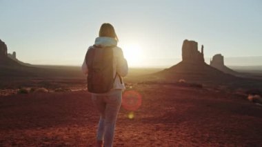 Gün batımı 4K, kadın turist manzaralı kızıl vadide altın gün batımının tadını çıkarıyor. 