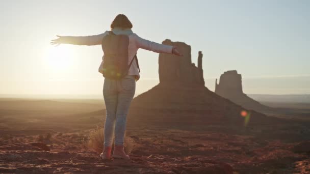 Jonge avontuurlijke vrouw op rots piek in slow motion, armen omhoog in vreugde, zonsopgang — Stockvideo