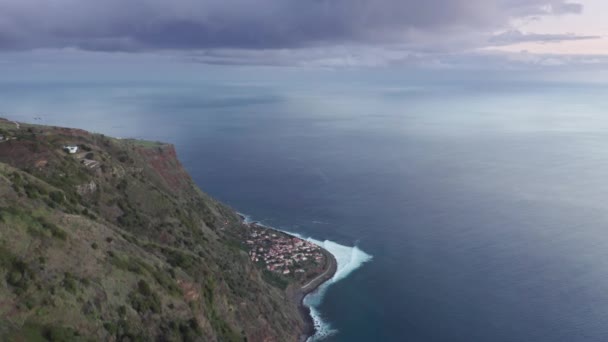 Luftaufnahmen einer windigen und steilen Landschaft mit einer Stadt unter einer Klippe — Stockvideo