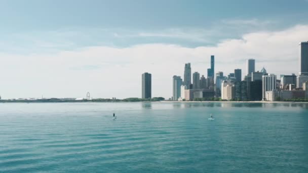 Hombre nadando en el tablero de paddle por el lago Michigan con fondo de paisaje urbano de Chicago — Vídeos de Stock