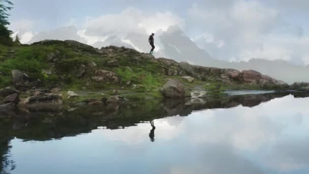 Jeune femme avec un sac à dos randonnée par sentier de montagne, sommet de neige sur fond — Video