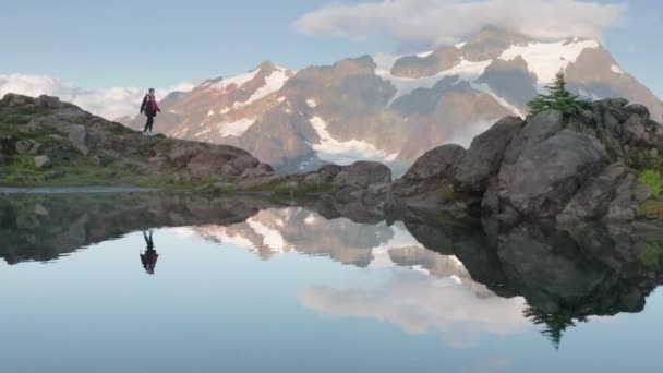 4K montanhas nevadas picos no fundo movimento, mulher caminhadas pelo lago geleira — Vídeo de Stock