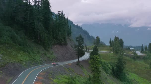 Епічний повітряний постріл автомобіля за кермом з хмарним гірським лісовим фоном, екологічний туризм — стокове відео