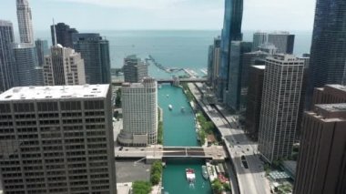 İHA Chicago nehri üzerinde, gökdelenlerin iş ofislerinin arasında geriye doğru uçuyor.