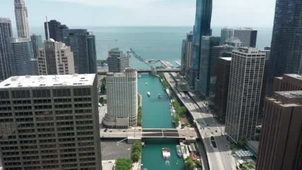 Drönare flyger bakåt över Chicago River, mellan skyskrapor kontor — Stockvideo