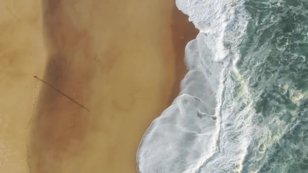 Habos hullámok csapódnak a sárgás partvonal felé, fentről nézve. — Stock videók