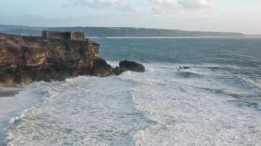 Mavi okyanus sularıyla çevrili kayalık uçurumun sinematik manzarası