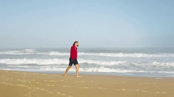 男は海岸線に沿って歩き絵のように巨大な潮を観察しながら — ストック動画