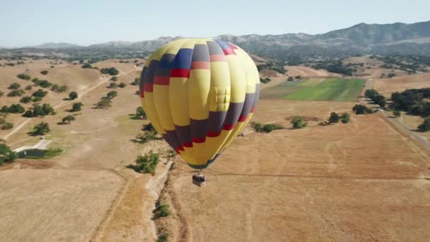 Kleurrijke hete lucht ballon epische vliegen op zonnige zomerdag bergen op de achtergrond — Stockvideo