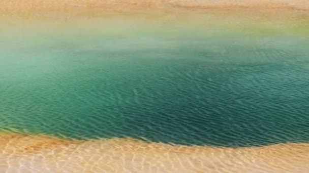 Прозрачная волнистая поверхность воды в ярко-зеленом бассейне глубокого вулканического гейзера — стоковое видео