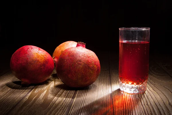 A glass of juice and a piece of ripe pomegranate — Stock Photo, Image