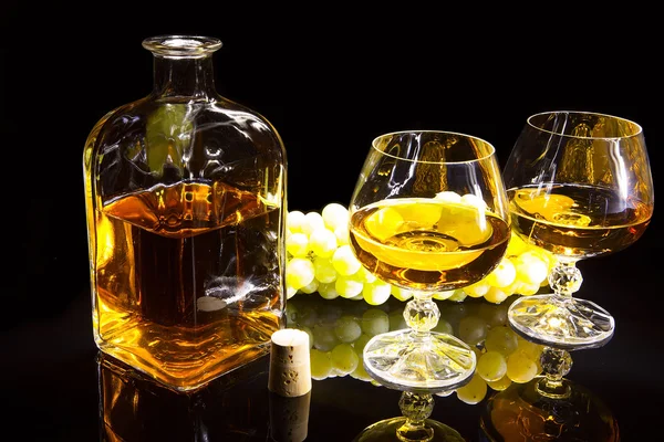 Bottle of brandy and two glasses and grapes — Stock Photo, Image