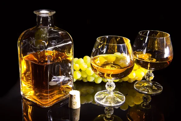 Bottle of brandy and two glasses and grapes — Stock Photo, Image