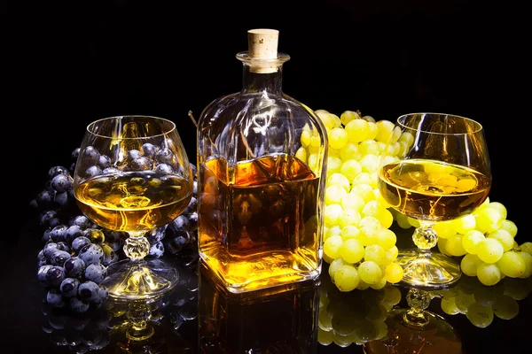 Bottle of brandy and two glasses and grapes — Stock Photo, Image