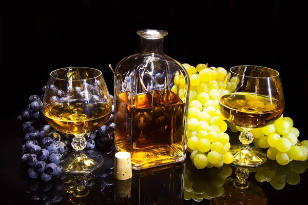 Bottle of brandy and two glasses and grapes — Stock Photo, Image