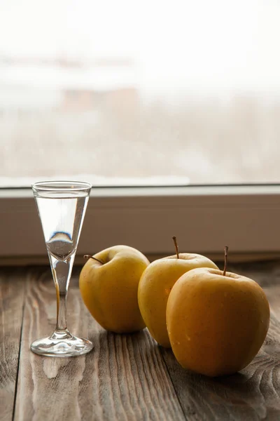 Стекло с коньяком Calvados и желтыми яблоками — стоковое фото