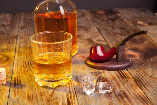 Bottiglia di whisky e una pipa di vetro e tabacco — Foto Stock