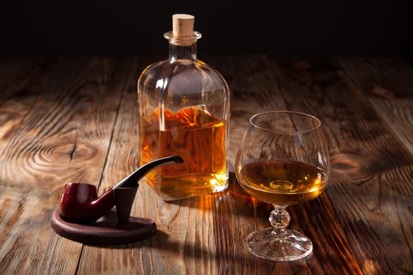 Bottle of brandy and a glass smoking pipe — Stock Photo, Image