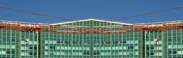 Arka planda ofis binası olan bir vinç. Kırmızı ve mavi. 