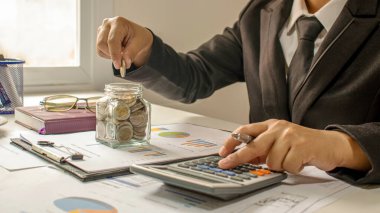 İşadamları işlerini sürdürülebilir para tasarrufu ve yatırım fikirleriyle finanse etmek için domuz kumbarasına madeni para koyarlar..