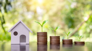 Model evler ve ağaçlar bozuk para yığınları üzerinde büyüyor. Kredi Konsepti Emlak Merdiveni Mali İpotek Konutu