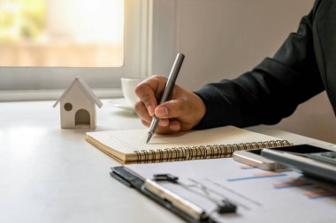 İşadamı masa başı işleri ve mali yönetim konseptiyle ilgili mali raporlar yazmak için kalem kullanıyor.