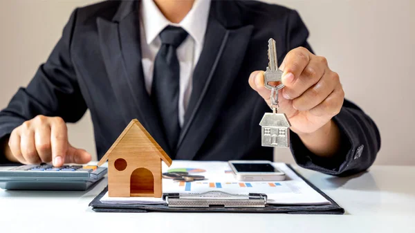 商人持有的房屋钥匙和木制房屋模型放在文件上金融概念抵押贷款和房地产 — 图库照片
