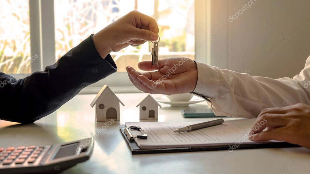 The real estate agent provides the house keys to the customer after signing the real estate contract with an approved mortgage request form. home mortgage loan concept and home insurance